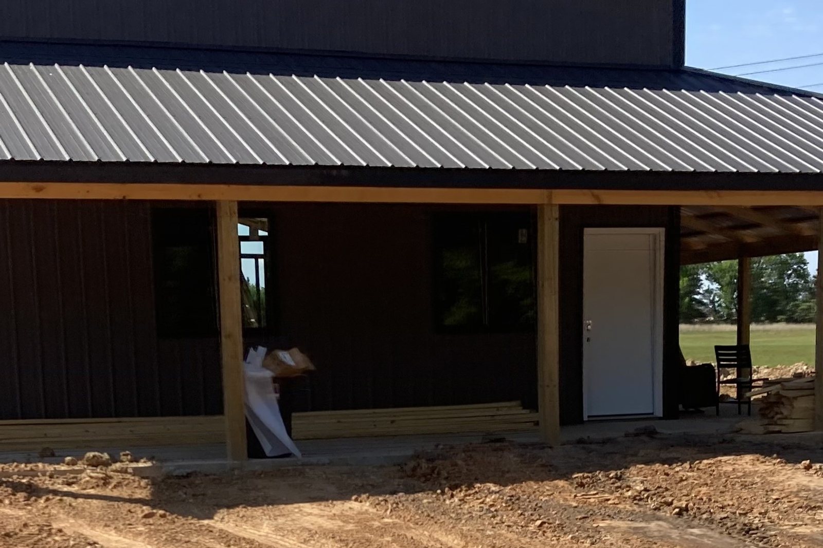 Dark metal building with a wood post porch and a metal roof