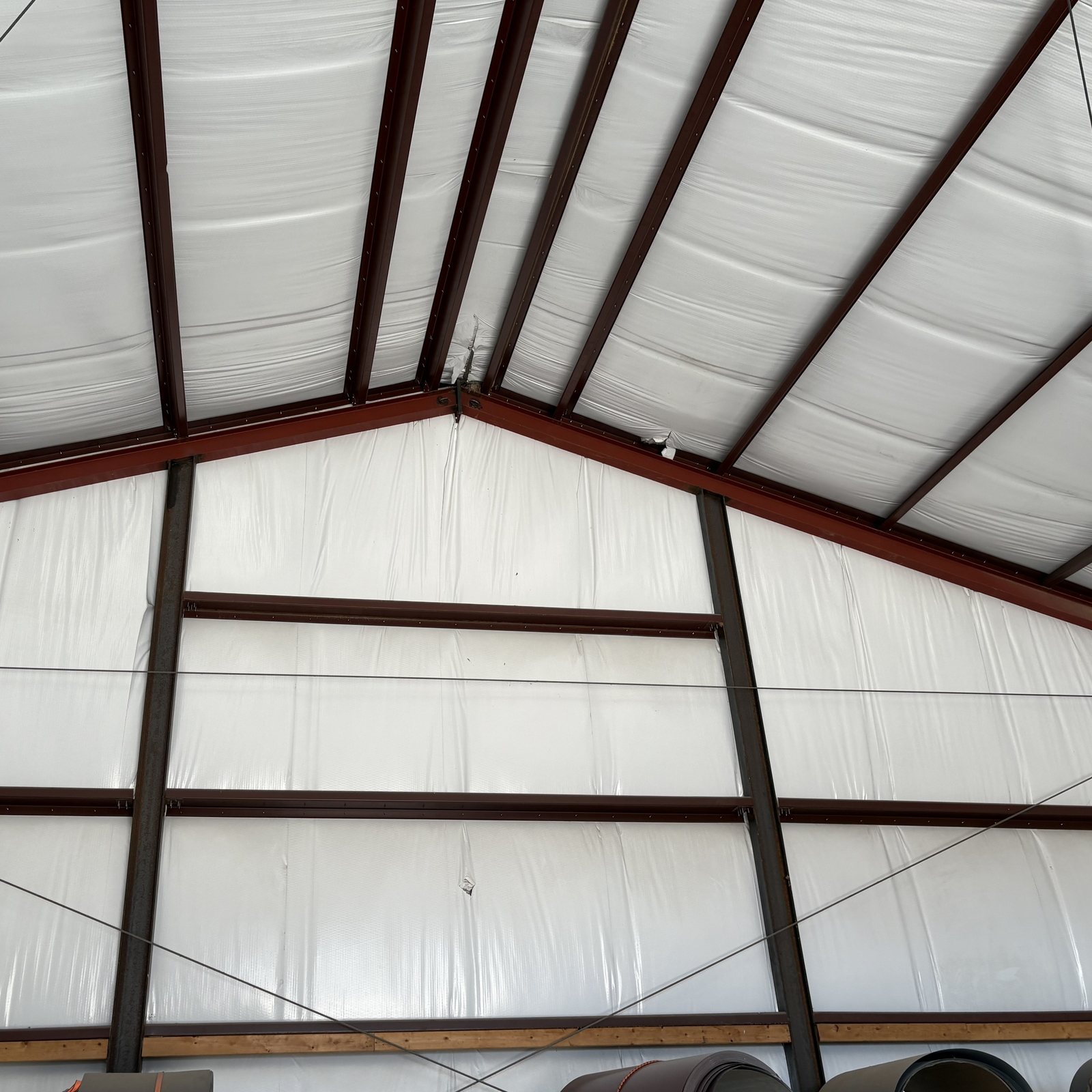 Red steel framing and white insulated panels inside a metal building